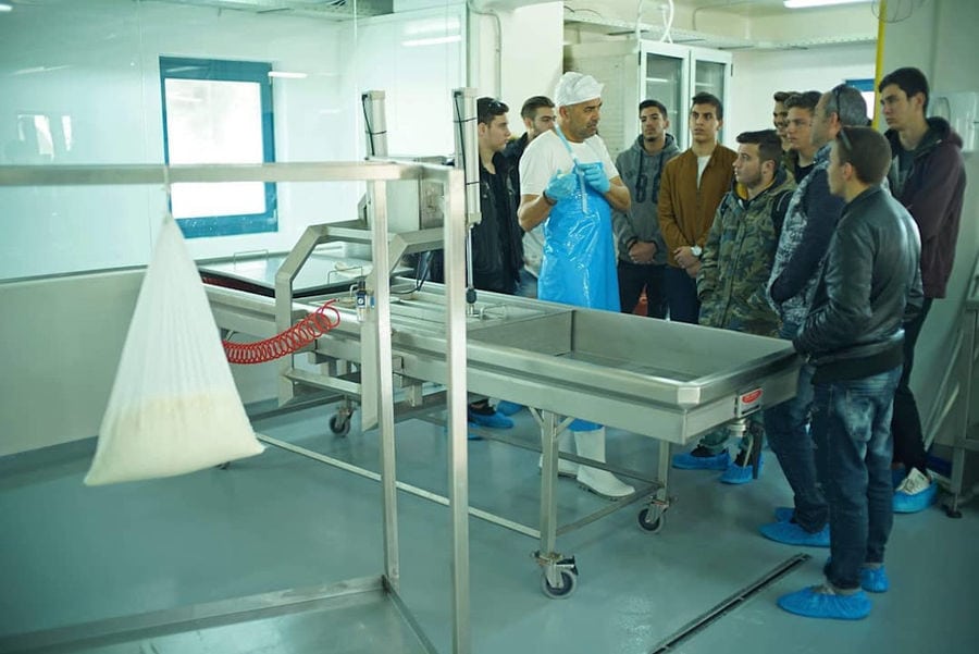 tourists front dairy equipment and listening to a man giving a tour at 'Mykonos Farmers' plant